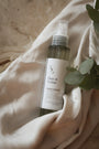 Vaporisateur d'ambiance Fleur de Cerisier LBL sur un drapé blanc satiné et feuille d'eucalyptus.