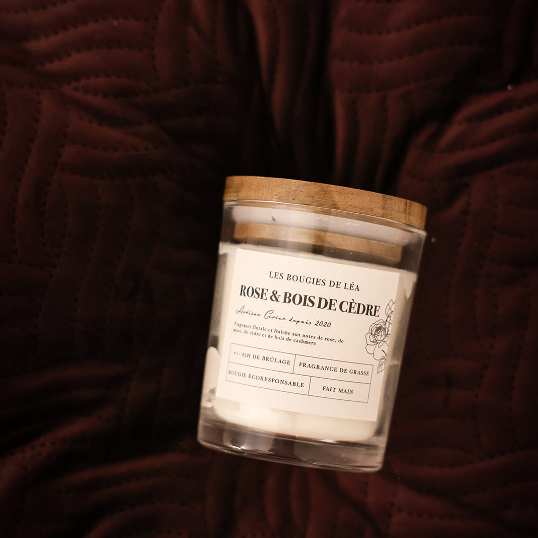 Bougie artisanale parfumée Rose & Bois de Cèdre Les Bougies de Léa sur un coussin en velours bordeau.