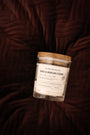 Bougie artisanale parfumée Rose & Bois de Cèdre Les Bougies de Léa sur un coussin en velours bordeau.