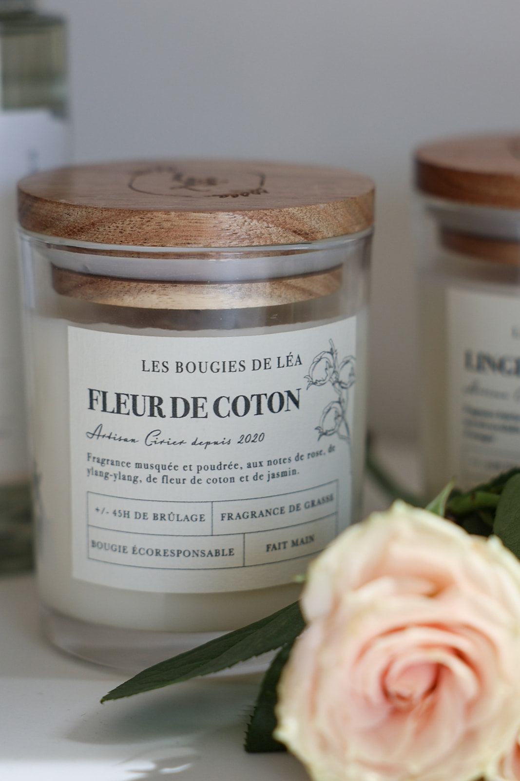 Bougie parfumée Fleur de Coton avec couvercle en bois, accompagnée d'une rose fraîche, idéale pour une décoration d'intérieur.