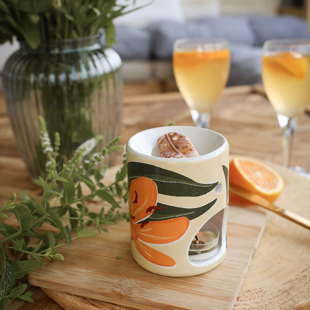 Brûle-parfum en céramique aux motifs floraux, fleur de Lys et estival, avec un fondant parfumé artisanal LBL et une bougie chauffe-plat, en extérieur avec oranges et cocktails.