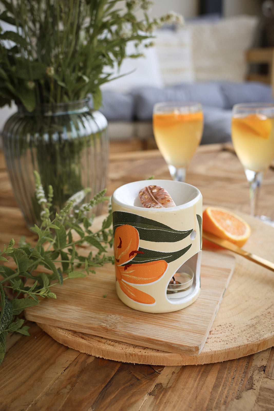 Brûle-parfum en céramique aux motifs floraux, fleur de Lys et estival, avec un fondant parfumé artisanal LBL et une bougie chauffe-plat, en extérieur avec oranges et cocktails.