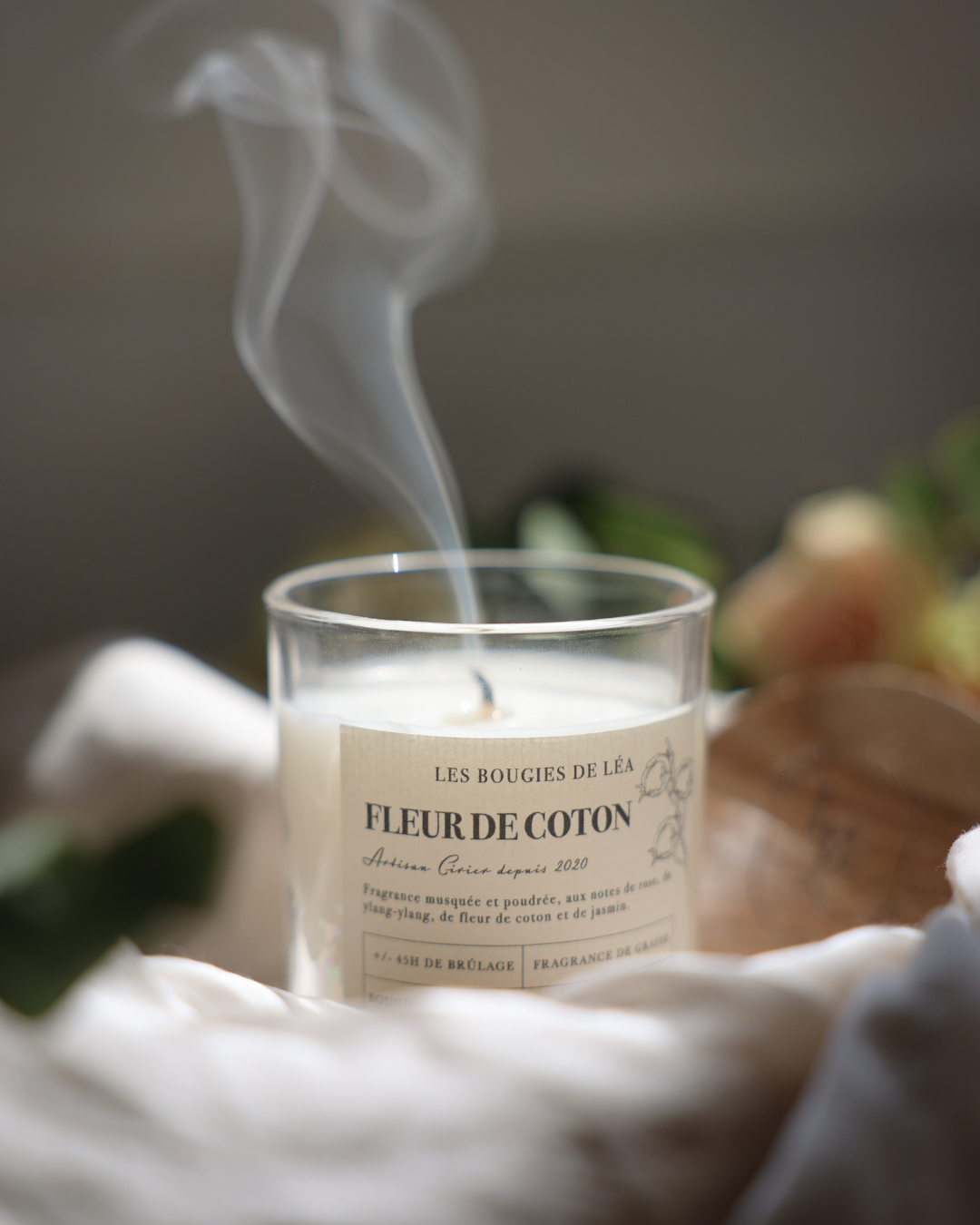 Bougie artisanale Fleur de Coton allumée dégageant un délicat filet de fumée dans une atmosphère cocooning.