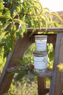 Bougies artisanales parfumées Les Bougies de Léa Pêche de vigne, dans les vignes, accompagnés de feuilles de pêchés, sur un tabouret en bois rustique et authentique, à la lumière du soleil.
