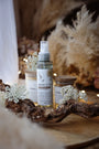 Brume d'ambiance végétale et parfumée LBL Ambre Floral Bois de Oud sur une table en bois dans une déco bohème chic avec fleurs blanches et bois
