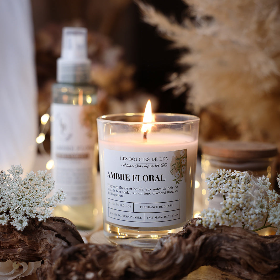 Bougie artisanale parfumée Ambre Floral Les Bougies de Léa allumée avec fleurs blanches et branche de bois, dans un déco bohème chic