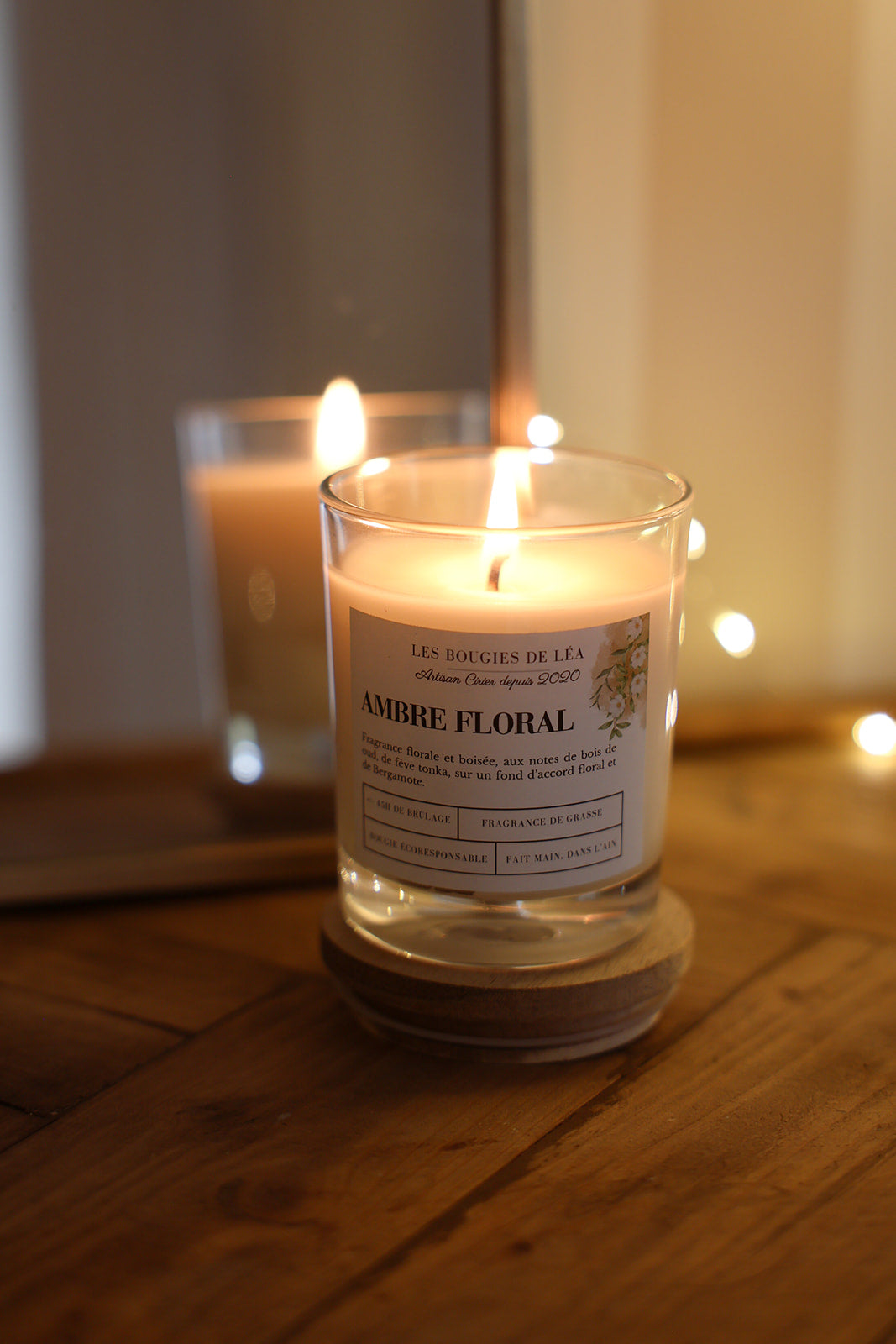 Bougie artisanale parfumée Ambre Floral Les Bougies de Léa allumée sur meuble en bois comme objet de décoration d'intérieur
