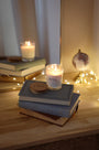 Bougies artisanales parfumées Orange et fève Tonka, orange cannelle allumée avec couvercles en bois d'acacia, sur livres, déco bohème chic, guirlande lumineuse.