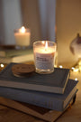 Bougies artisanales parfumées Orange et fève Tonka, orange cannelle allumée avec couvercles en bois d'acacia, sur livres, déco bohème chic, guirlande lumineuse.