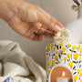 Main déposant un fondant parfumé Douce couverture LBL sur un brûle-parfum en céramique et motif fleuri, accompagné d'une bougie chauffe-plat allumée.